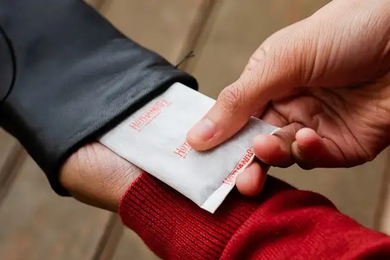 A person putting a hand warmer inside their glove