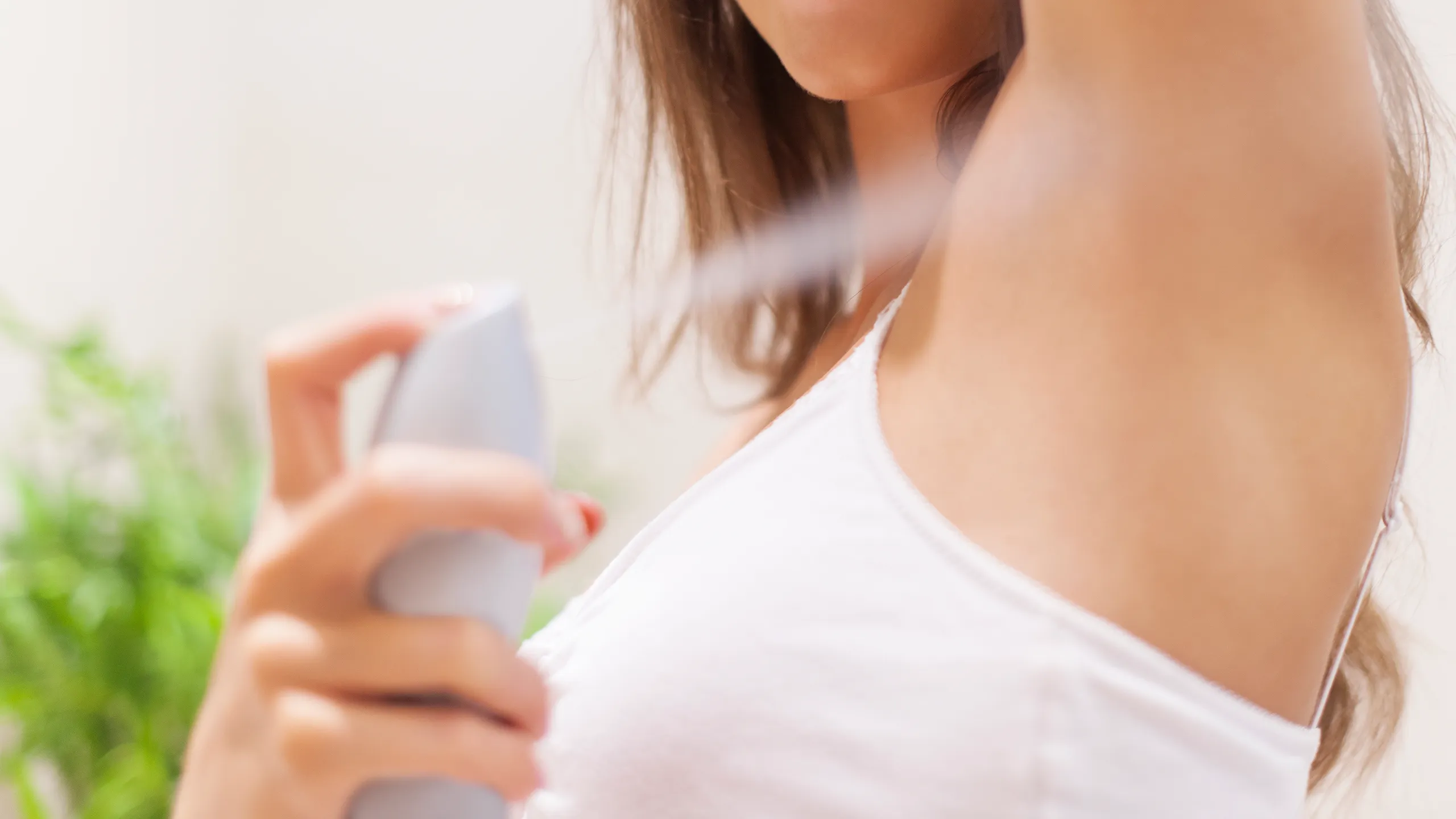 A woman using spray deodorant