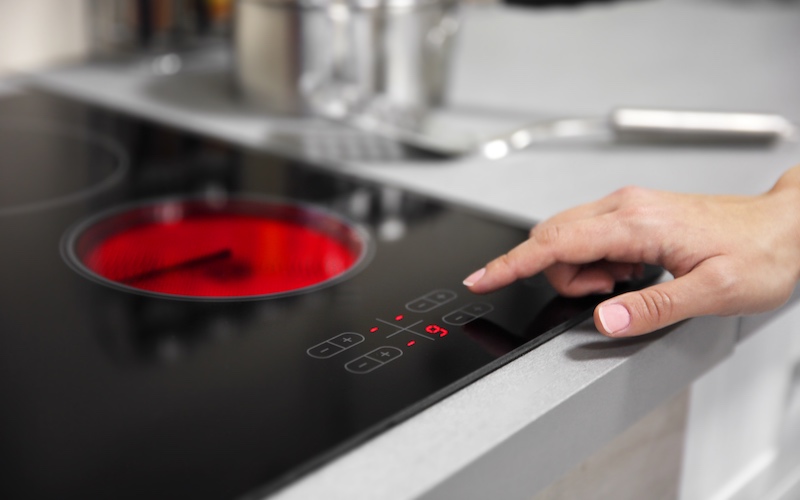 A female hand turning on the electric hob