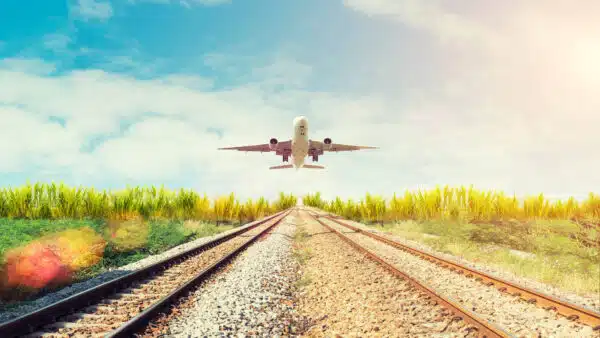 An airplane flying over a train rail track.